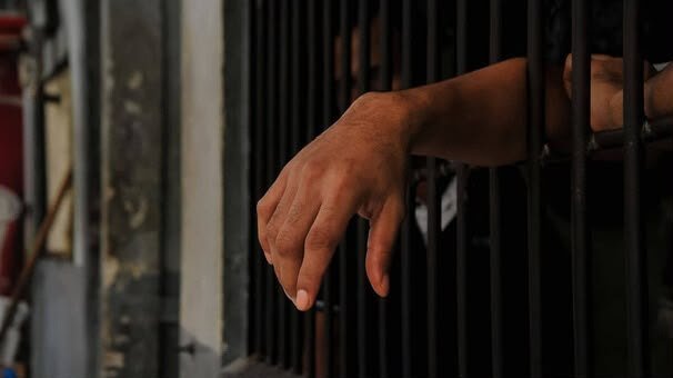 Una mano asomada entre los barrotes de una celda