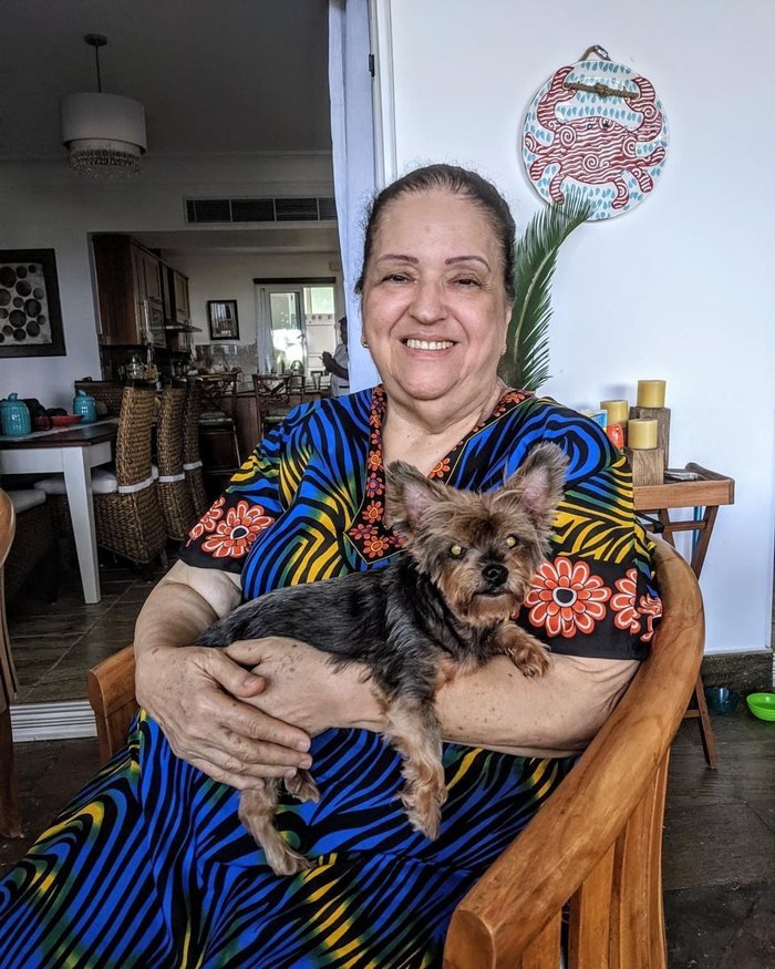 Ivonne Handal sentada en su casa, sosteniendo a su perrita en el regazo
